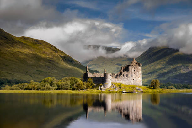 A misty, scenic view of a loch and ancient castle in the Scottish Highlands.